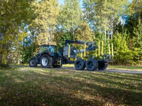 Traktor med en PALMS 7.87 skogskran montert på en tømmertilhenger på en skogsvei.