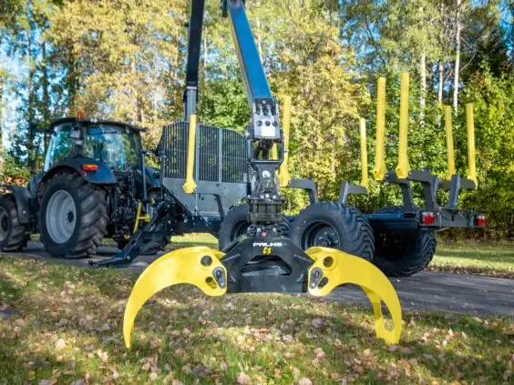 En kraftig PALMS 7.87 skogskran montert på tømmervogn med gul gripeklo foran.
