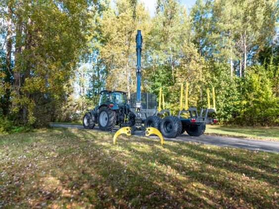 Traktor med tømmertilhenger og PALMS 7.87 skogskran parkert på en skogvei.