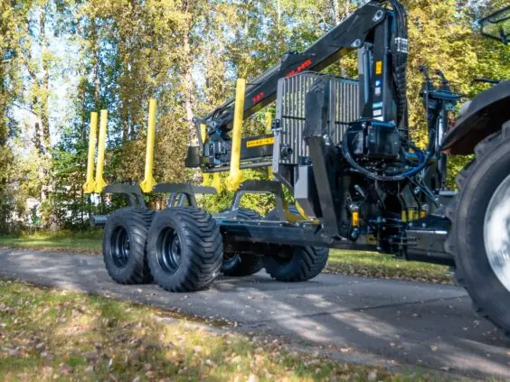 Tømmertilhenger med PALMS 7.87 skogskran på en skogsvei om høsten.