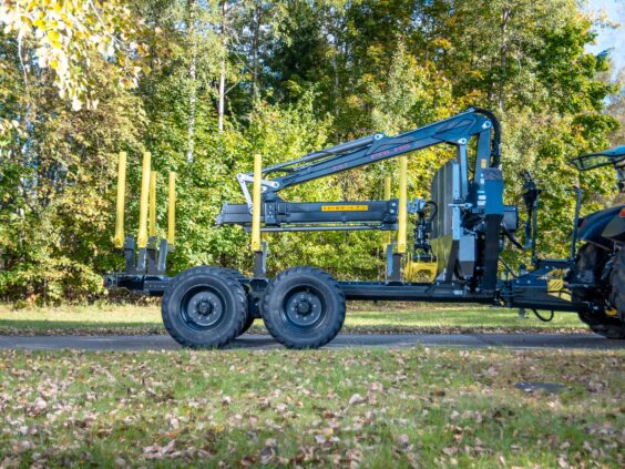 Robust tømmervogn med en PALMS 7.87 skogskran parkert foran grønne skogstrær.
