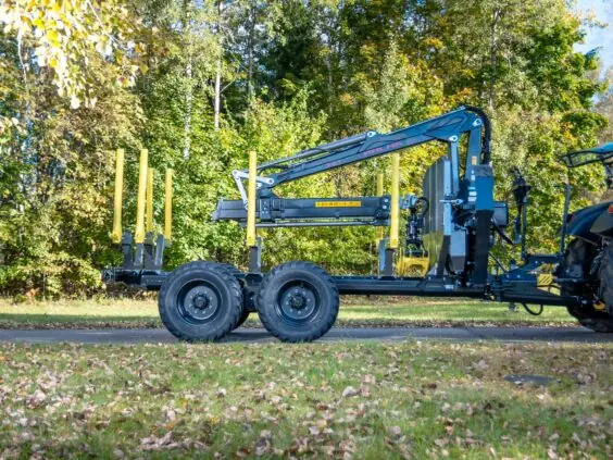Robust tømmervogn med en PALMS 7.87 skogskran parkert foran grønne skogstrær.