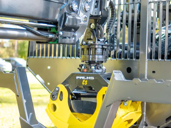 Nærbilde av tømmerkloen og hydraulikken på en PALMS 7.87 skogskran utendørs.