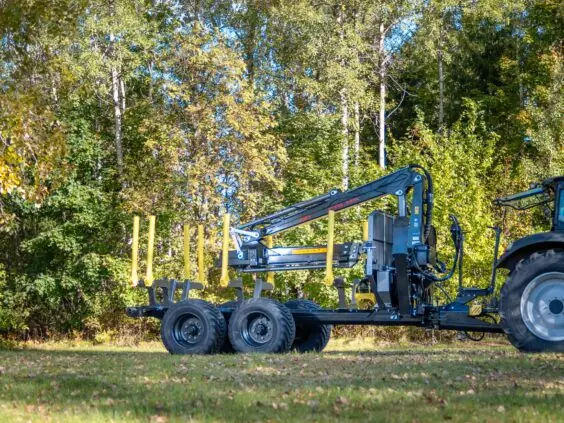 En robust PALMS 7.87 skogskran montert på en tømmertilhenger i skogsmiljø.