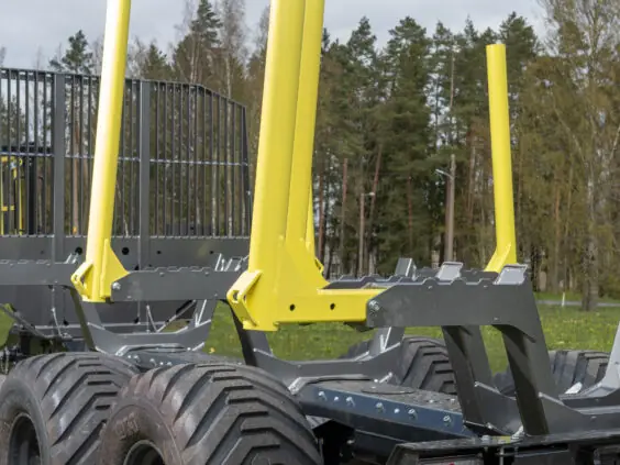 En robust PALMS 11UX tømmervogn med gule staker og store hjul parkert utendørs.