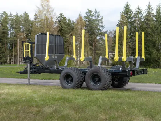 Robust PALMS 11UX tømmervogn parkert på en vei ved siden av en skog.