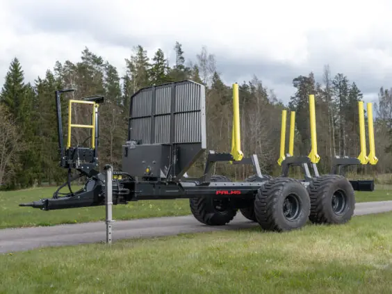 Robust PALMS 11UX tømmervogn parkert på en vei ved siden av en skog.