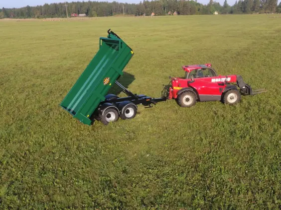 Rød Manitou teleskoplaster med grønn ML414-PS – hooklift på et grønt jorde.