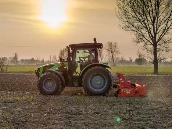 Grønn Deutz-Fahr Series 5 Keyline traktor i arbeid på en åker ved solnedgang.
