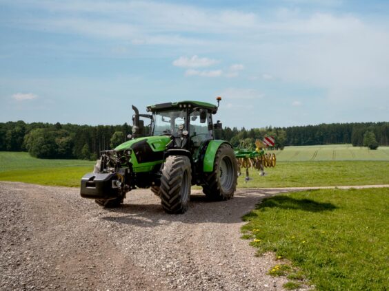 Grønn Deutz-Fahr Series 5 traktor på en grusvei i et vakkert jordbrukslandskap.