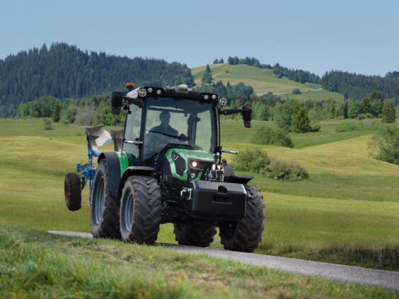 Grønn Deutz-Fahr Series 5D TTV traktor med plog som kjører på en landevei.