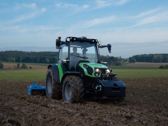 Grønn Deutz-Fahr Series 5D TTV traktor som arbeider på en åker under blå himmel.