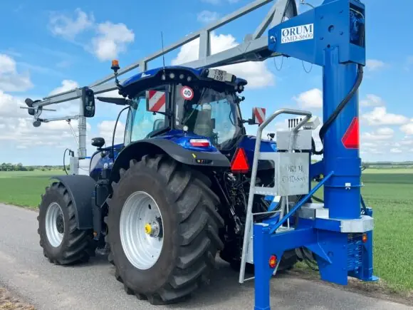 En blå traktor utstyrt med en ØRUM GMD-8600 gjødselmikser: stående på en vei.