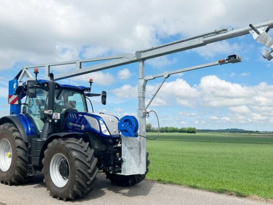 Blå traktor med en montert ØRUM GMD-8600 gjødselmikser i et åpent landskap.