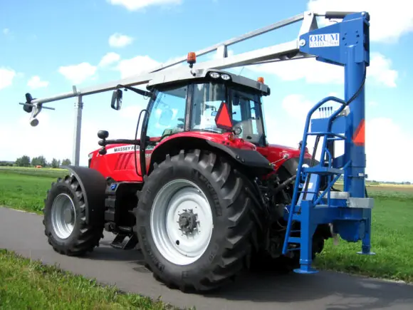 Rød Massey Ferguson traktor utstyrt med en ØRUM GMD-7500 gjødselmikser stående på asfaltvei.