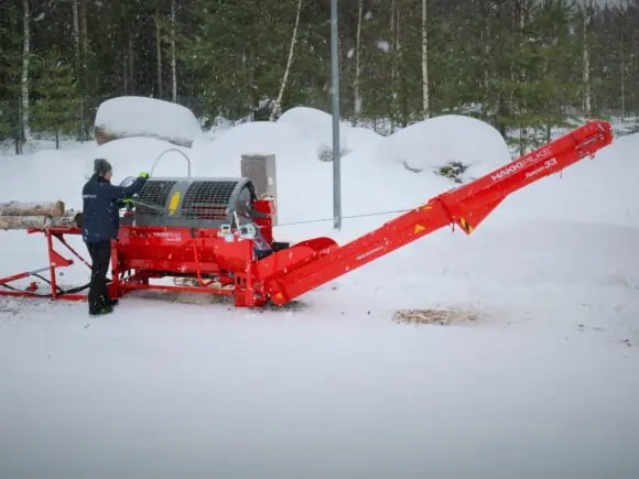 Rød Hakki Pilke Raven 33 vedmaskin i bruk utendørs i et snødekket landskap.