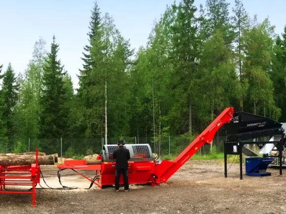 En operatør som bruker Hakki Pilke 38 Pro vedmaskin i et skogsområde.