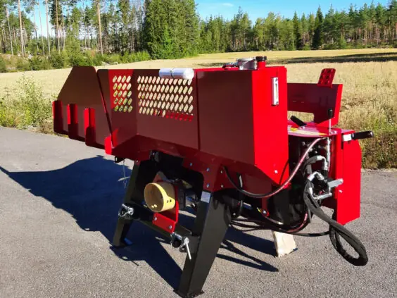 En rød Hakki Pilke HH 110 vedmaskin står utendørs på en asfaltert vei.