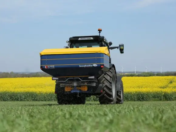 Bogballe L15W plus kunstgjødselspreder montert bak på en traktor i et grønt felt.
