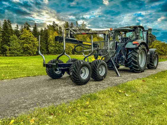 Robust PALMS 6S tømmervogn med kran koblet til traktor på en landevei.