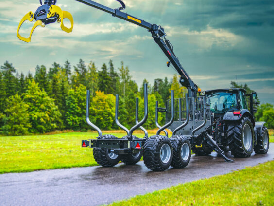 En moderne PALMS 9SC tømmervogn med kran koblet til en traktor på en vei.