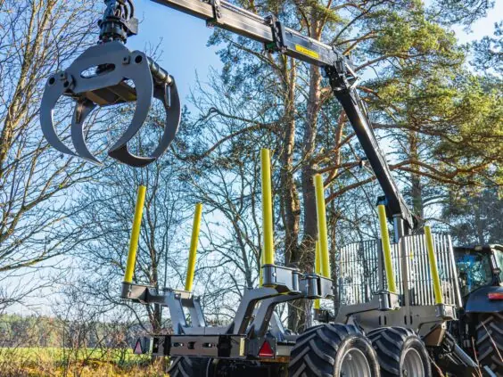 Robust PALMS 5.85 skogskran montert på en tømmervogn i et solfylt skoglandskap.