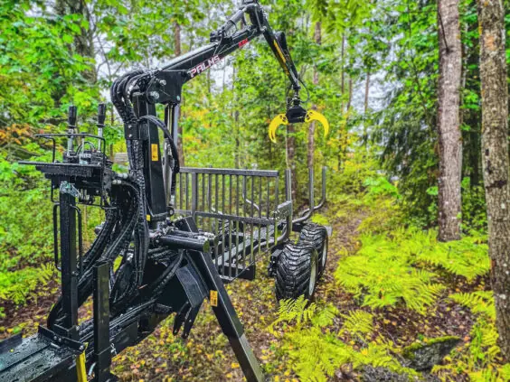 PALMS 6S tømmervogn med tømmerkran stående på en sti i en grønn skog.