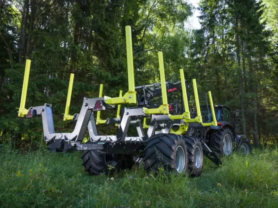 En PALMS HMWD 3.2 tømmervogn koblet til en traktor i en grønn skog.