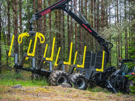 Robust PALMS X100 skogskran montert på tømmervogn i en grønn skog.