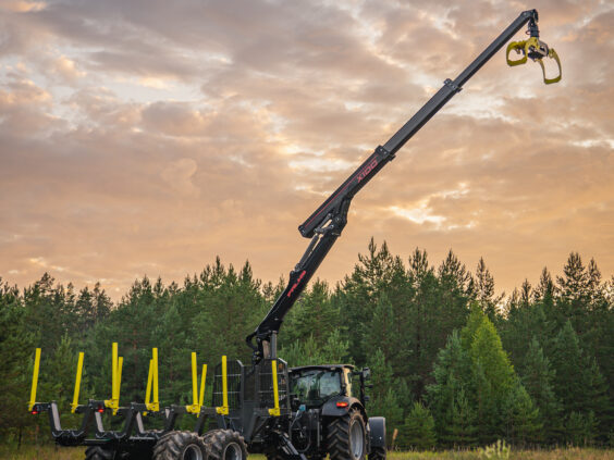 Traktor med tømmerhenger og en fullt utstrakt PALMS X100 skogskran mot en vakker solnedgang.
