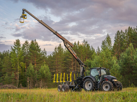 Svart traktor med en fullt utstrakt PALMS X100 skogskran og tømmertilhenger på et jorde.