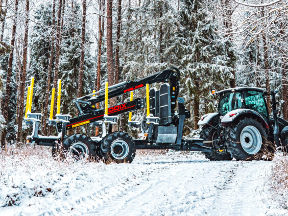 En PALMS HMWD 3.2 tømmervogn koblet til en traktor på en snødekket vei i skogen.