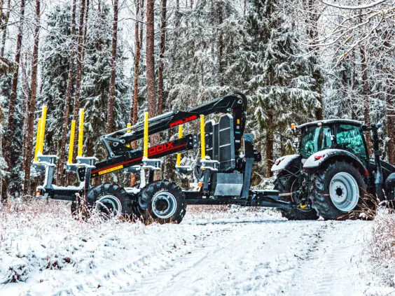 En PALMS HMWD 3.2 tømmervogn koblet til en traktor på en snødekket vei i skogen.