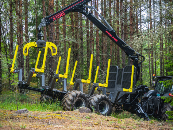 En robust PALMS HMWD 3.2 tømmervogn med kran står klar i en tett furuskog.