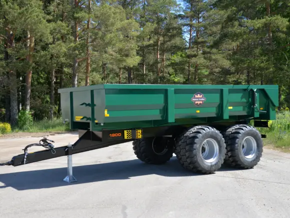 Grønn Palmse PT1900MB dumperhenger parkert på asfalt med skog i bakgrunnen.