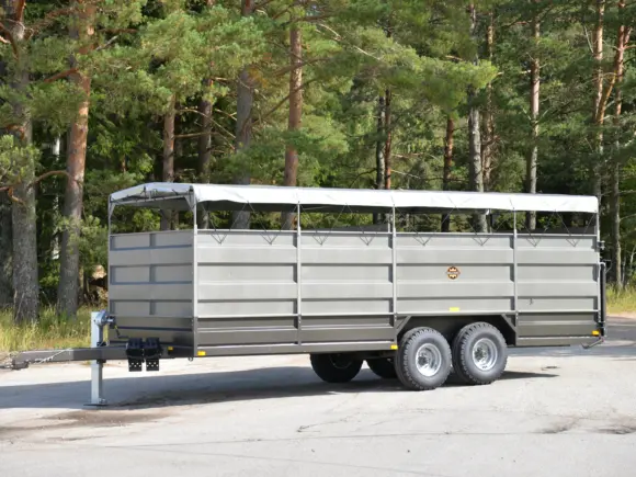 Robust grå PT4650 dyrehenger med hvit presenning parkert foran en skog.
