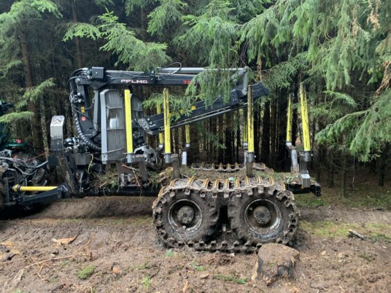 En robust PALMS MWD 3.2 tømmervogn med belter i et gjørmete skogsterreng.