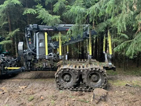 En robust PALMS MWD 3.2 tømmervogn med belter i et gjørmete skogsterreng.