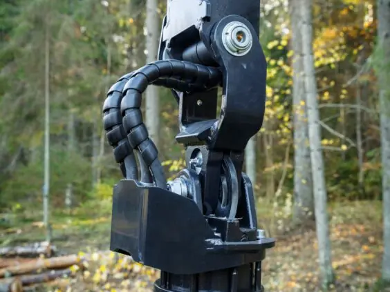 Nærbilde av hydrauliske koblinger og ledd på en PALMS 7.94 skogskran i skogen.