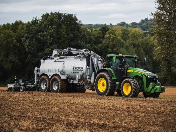 En John Deere traktor som trekker en Pichon SV-serien vakumvogn over en åker.
