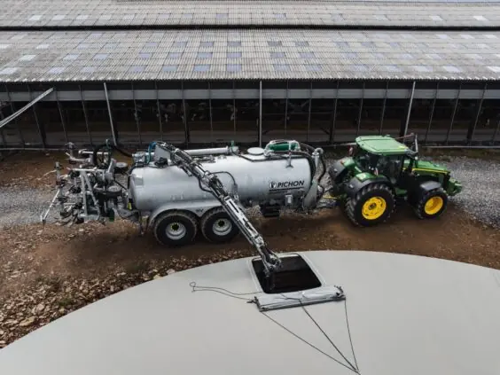 En John Deere-traktor som bruker Pichon fyllesystemer for vakumvogner ved en gjødselkum.