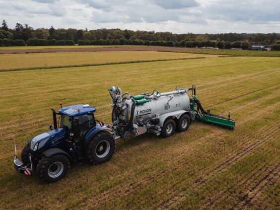 En blå traktor trekker en Pichon SV-serien vakumvogn over et jorde.