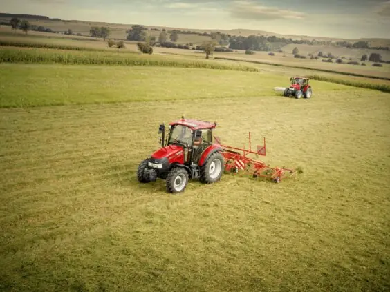 To Case IH Farmall i arbeid med høyvender på eng