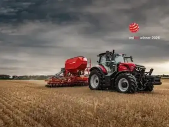 En rød Case IH traktor fra Puma-serien i arbeid på en åker ved solnedgang.