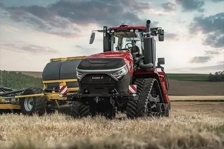 En rød Steiger 785 Quadtrac traktor i arbeid på en åker under en overskyet himmel.