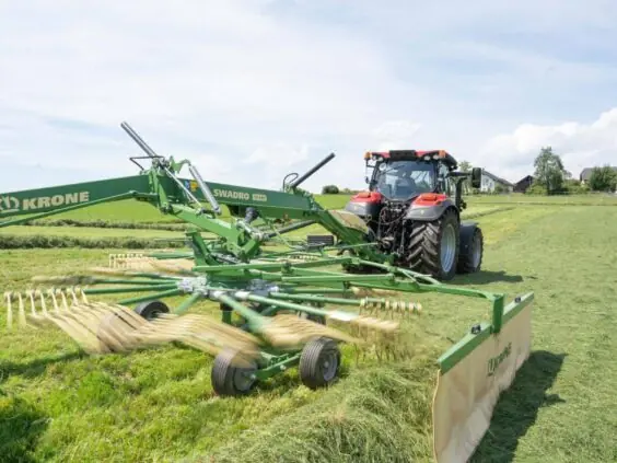 Rød Case IH traktor fra Vestrum-serien i arbeid med en Krone Swadro rake.