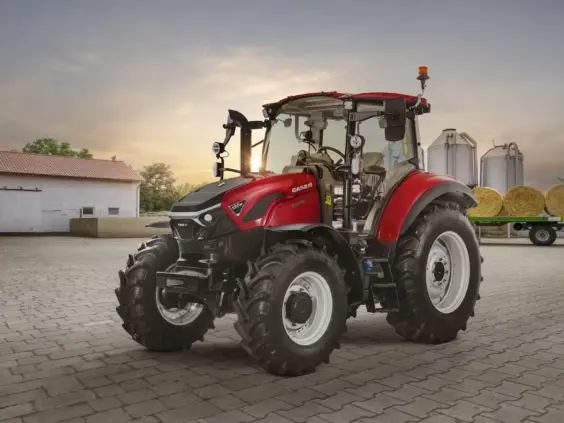 Rød Case traktor parkert på en gårdsplass med siloer i bakgrunnen.
