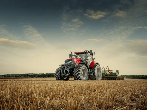 Rød Case IH Puma traktor i arbeid på en høstet kornåker under blå himmel.