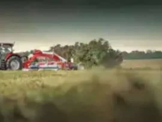 Rød Case IH-traktor fra Puma-serien som arbeider på en åker ved solnedgang.