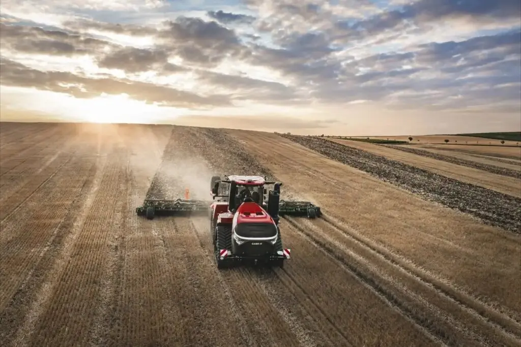 En rød Steiger 785 Quadtrac traktor i arbeid på en åker ved solnedgang.